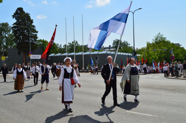 Karjalaisten kesäjuhlien juhkakulkueen etummaisena Suomen lippu.